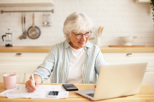 people-age-technology-and-occupation-concept-indoor-image-of-attractive-smiling-gray-haired-woman-pensioner-using-laptop-for-remote-work-sitting-in-kitchen-LEVE